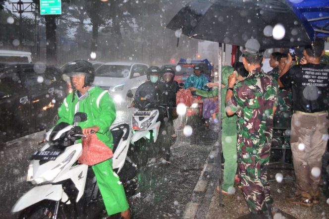 
 Anggota Korem 083/Bdj bersama ibu Persit KCK, saat membagikan takjil di tengah hujan lebat (Penrem 083/Bdj)
