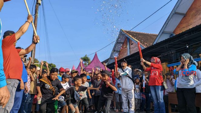 
 Kepala Desa Tambakasri Teguh Wiyono (kiri baju orange), didampingi sang istri (kanan memegang party popper) dan Kepala Sekolah SDN 1 Tambakasri Achmad Saiful Arif melepas peserta jalan sehat di Depan SDN 1 Tambakasri, Minggu (21/5/2023) Kecamatan Tajinan, Kabupaten Malang. (wahyu)