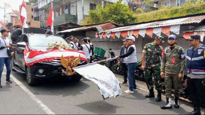 
 Kades Punten Hening Trisunu, saat memberangkatkan para peserta karnaval dengan mengibarkan bendera. (Yan)