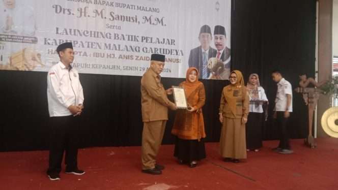 
 Anis Zaida menyerahkan kain batik Garudeya kepada dua perwakilan siswa dari SMP 3 Muhamadiah di Hall Bojana Puri Kepanjen, Kabupaten Malang, Senin (29/4/2024). (yon)