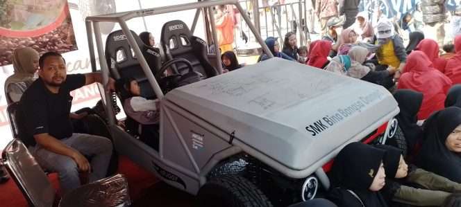 
 Ketua Tim Pameran SMK Bina Bangsa, Thaufan Firdaus SPd, berfoto bersama mobil listrik. (ist)