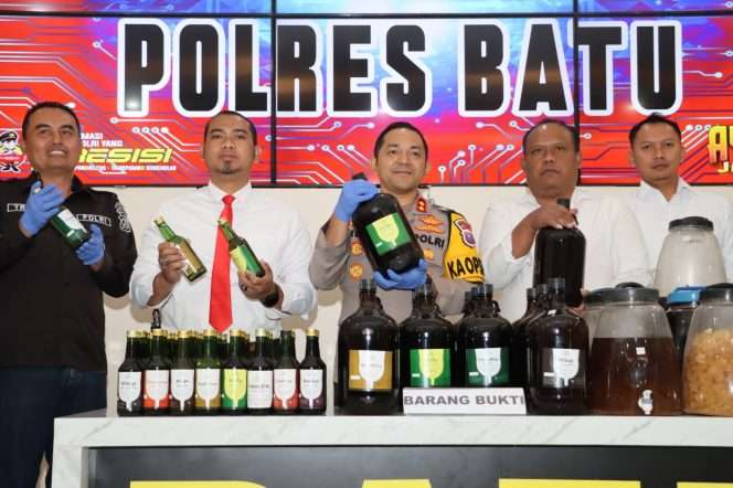 
 Kapolres Batu, AKBP Andi Yudha Pranata, S.H., S.I.K., M.Si., didampingi oleh Kasat Resnarkoba Polres Batu, Iptu Ariek Yuly Irianto, S.H., M.M., dan Kasihumas Polres Batu, Iptu Trimo Wahyudi, S.H saat menunjukkan botol miras ilegal yang berhasil disita dalam press release yang digelar di Rupatama, Polres Batu. (Yan)