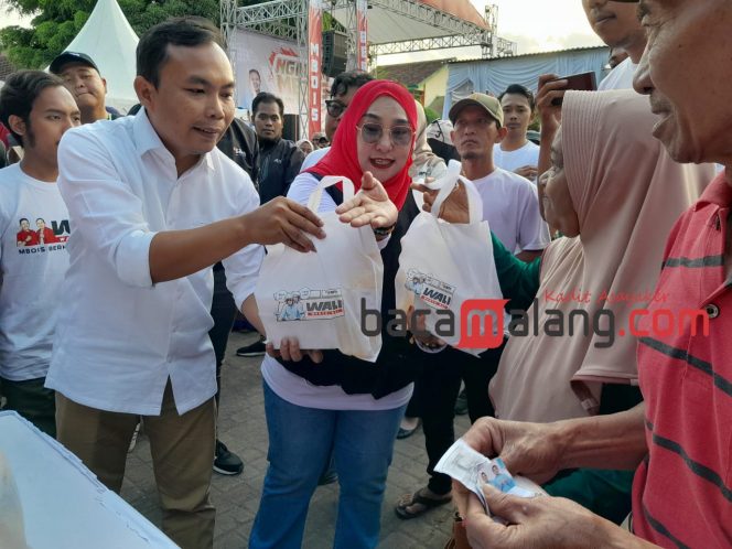 
 Ali Muthohirin saat menyerahkan sembako murah kepada salah seorang warga di ngalam mbois fest. (Rohim Alfarizi)
