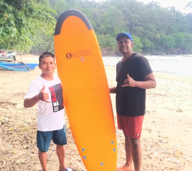 
 Mukhlis dan Reynold Mark, wisatawan Amerika Serikat, berrfoto bersama membawa papan selancar baru. (Pokdarwis Bowele for BacaMalang)