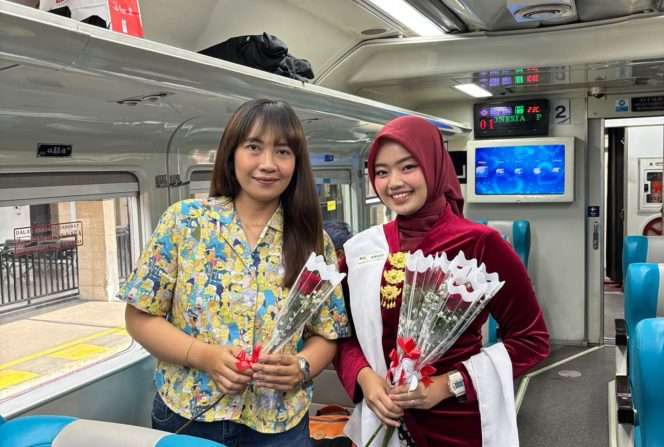 
 Petugas frontliner KAI mengenakan seragam saat membagikan bunga kepada penumpang di dalam gerbong kereta. (ist)