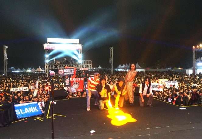 
 Para personel Slank dalam formai lengkap dengan latar belakang Slankers saat Tur HS x Slank Lapangan Rampal, Malang, Minggu (19/4/2026) (Nedi Putra AW)
