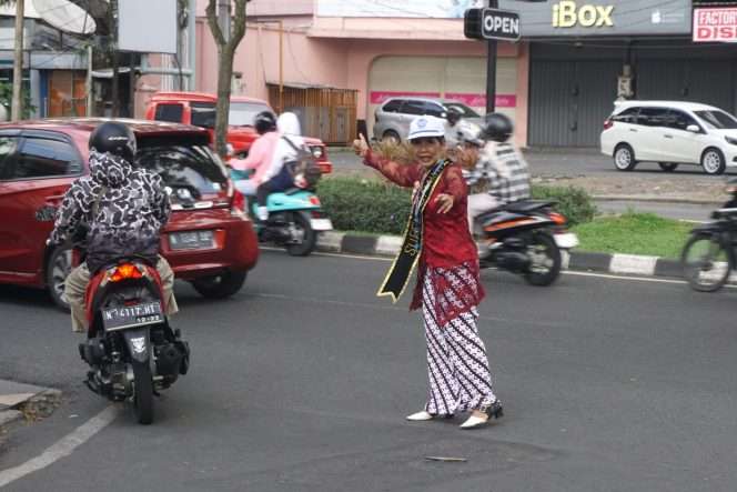 
 Sukarni mengenakan kebaya saat bertugas di pertigaan Jalan Semanggi Timur dan Jalan Soekarno Hatta, Kota Malang, Selasa (21/4/2026). (Nedi Putra AW)