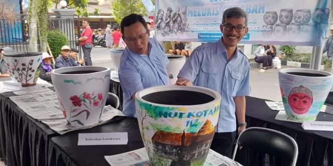 
 Camat Lowokwaru, Rudi Cahyono, bersama Sekretaris Kecamatan Lowokwaru saat melihat lukisan gerabah karya salah satu peserta lomba. (ist)