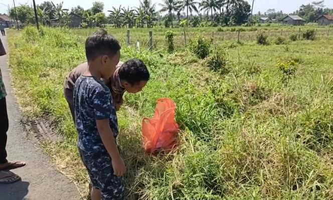 
 Jenazah bayi laki-laki di dalam tas kresek berwarna merah digeletakkan di pinggir jalan menjadi perhatian warga. (IG Lawangku)