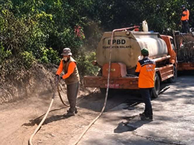 
 Personel BPBD merapikan selang penyemprot air usai api padam di lokasi kebakaran. (Purwoto for bacamalang)