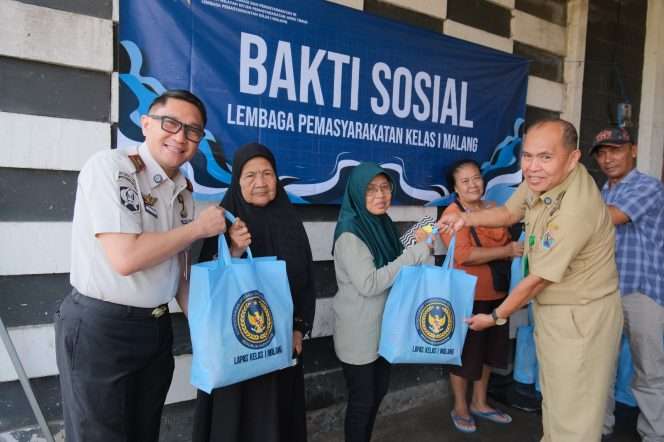 
 Kalapas Kelas I Malang Christo Victor bersama Lurah Buring saat menyerahkan bingkisan kepada warga sekitar usai kegiatan bakti sosial membersihkan TPU Buring. (ist)