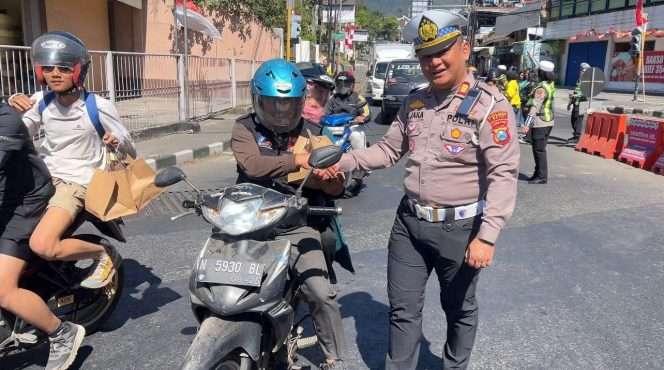 
 Kasatlantas Polres Batu, AKP Matheus Jaka Iswantara, S.H., M.H saat tengah memberikan tali asih berupa paket Sembako kepada pengendara yang melintas dan Ojol. (Yan)
