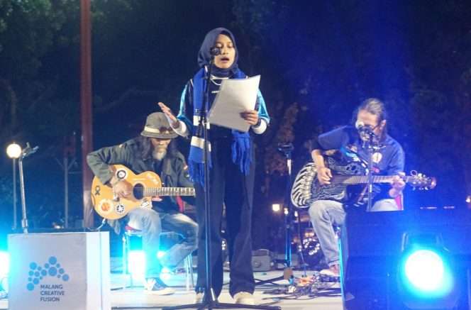 
 Duet gitar akustik Antok Yunus, dan Wahyu Arema Voice mengiringi Janata Lavanya Leticia Zulkarnain dengan puisi bertajuk Melodi di Bumiku: Malang yang Kucintai dalam Road to Festival Mbois 11 *“Malang Menyala”, di Alun-Alun Kota Malang, Selasa (11/8/2026). (Nedi Putra AW)