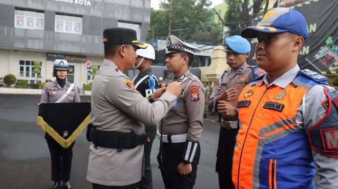
 Kapolresta Malang Kota, Kombes Pol Danang Setiyo P.S., memasangkan pita kepada salah satu petugas dalam kegiatan Operasi Patuh Semeru 2026. (ist)